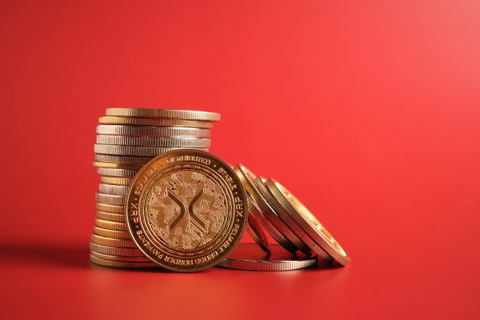 Das Bild zeigt XRP-Münzen auf rotem Hintergrund.