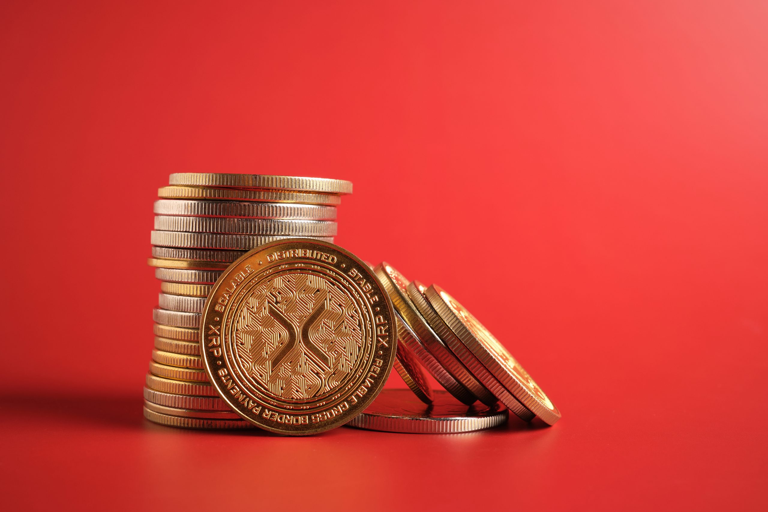 Das Bild zeigt XRP-Münzen auf rotem Hintergrund.