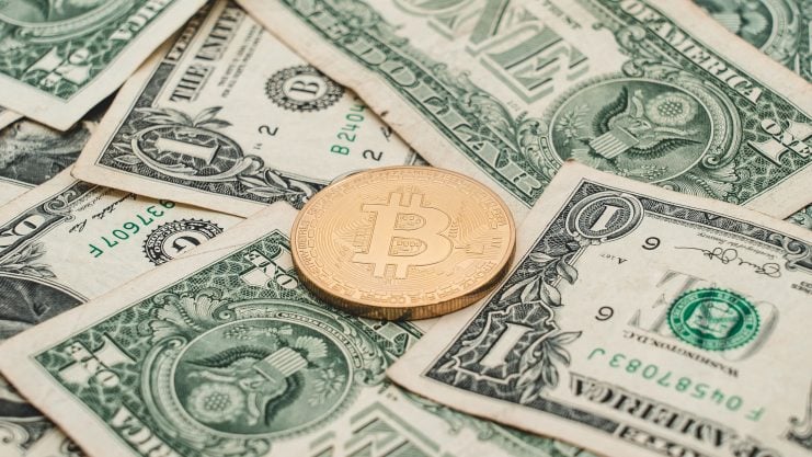 Das Bild zeigt eine Bitcoin-Münze auf US-Dollar-Scheinen