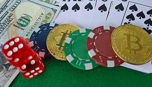 Das Bild zeigt Bitcoin-Münzen neben Spielkarten und Würfeln