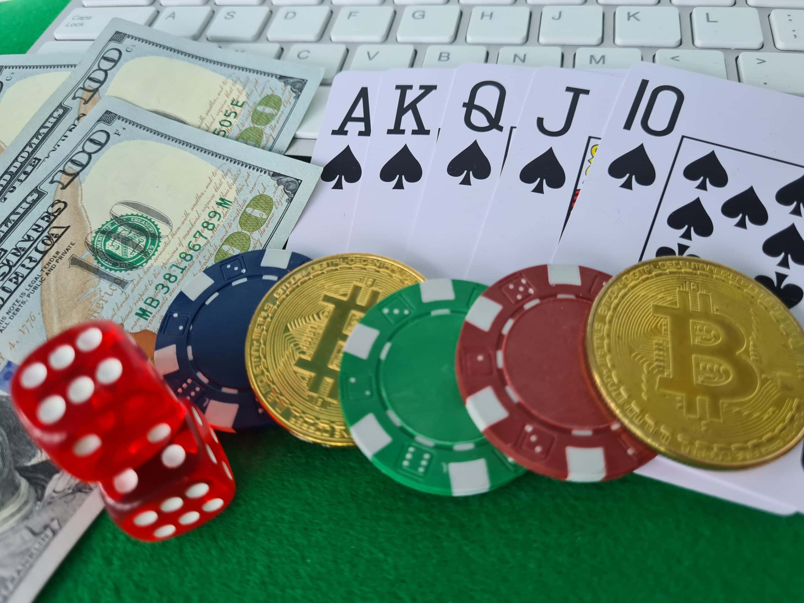 Das Bild zeigt Bitcoin-Münzen neben Spielkarten und Würfeln