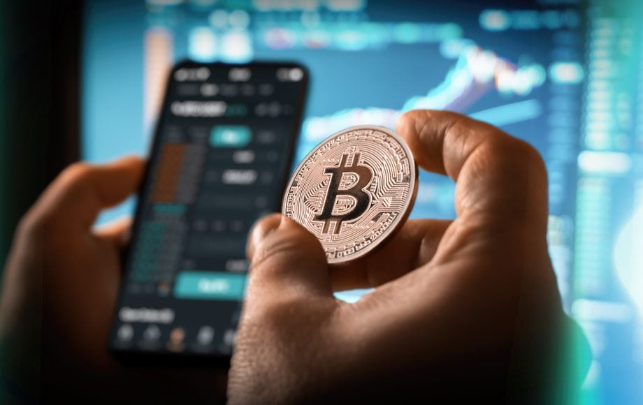 Eine Hand hält eine Bitcoin-Münze