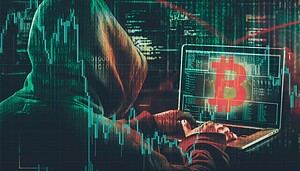 Symbolbild einer vermummten Person am Laptop vor Kursverläufen und einem Bitcoin-Symbol.