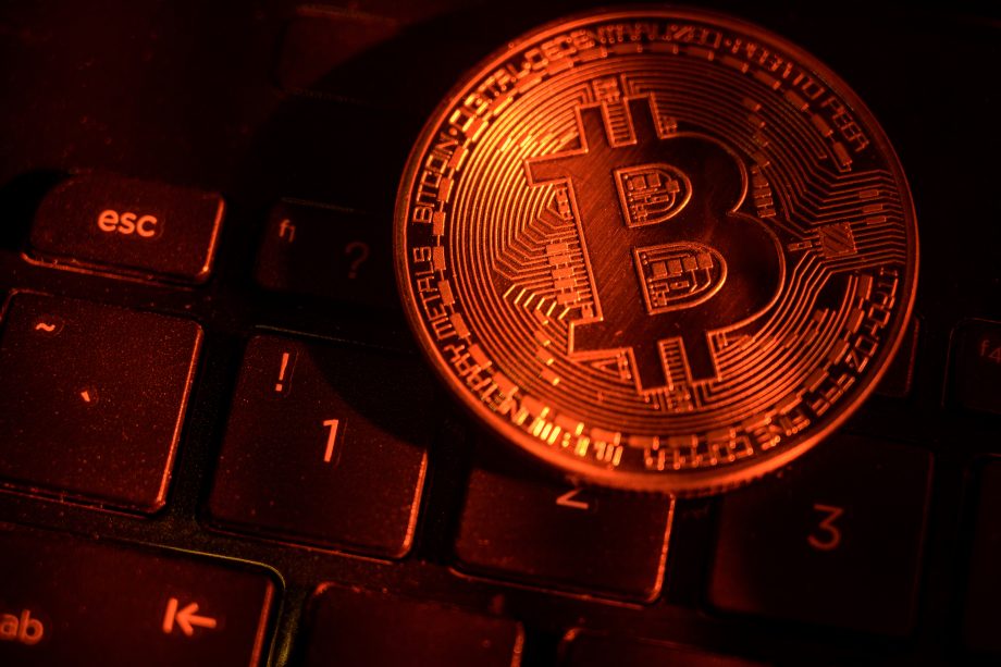 Eine rot beleuchtete Bitcoin-Münze liegt auf einer Tastatur
