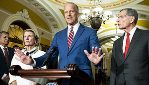 Ein weißer Mann im marineblauen Anzug steht vor einem Rednerpult und spricht zu Journalisten.