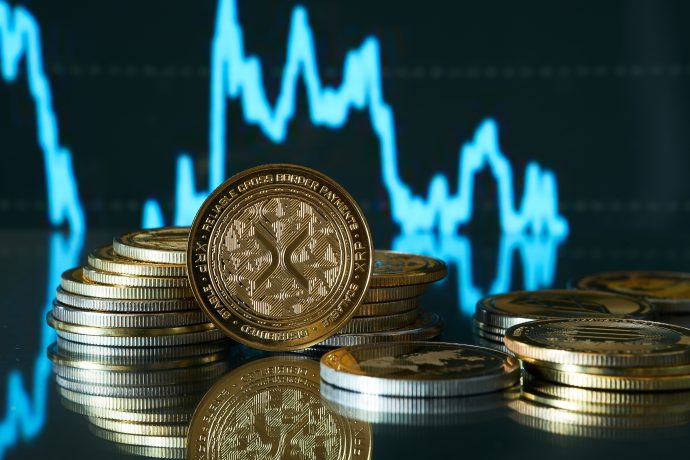 Das Bild zeigt eine XRP-Münze und einen blauen Kurschart.