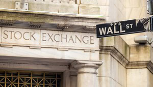 Vor der Steinfassade der New Yorker Börse ist ein Straßenschild der Wall Street angebracht, das die Überschneidung von traditionellem Finanzwesen und modernen Vermögenswerten wie Bitcoin hervorhebt.