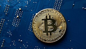 Das Bild zeigt eine Bitcoin-Münze auf einer Platine.