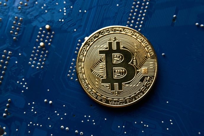 Das Bild zeigt eine Bitcoin-Münze auf einer Platine.