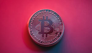 Man sieht eine Bitcoin-Münze vor einem roten Hintergrund.