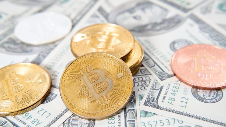 Ist der Anstieg nachhaltig? Das Bild zeigt eine Bitcoin-Münze auf US-Dollar-Scheinen