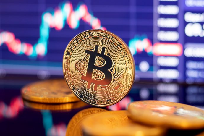 Eine Bitcoin-Münze vor einem Chart
