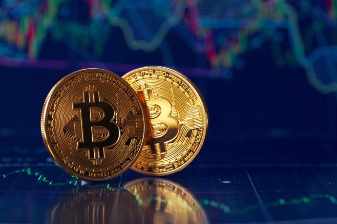 Zwei Bitcoin-Münzen vor einem Chart