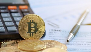Eine Bitcoin-Münze vor einem Taschenrechner