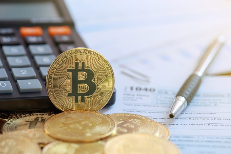 Eine Bitcoin-Münze vor einem Taschenrechner