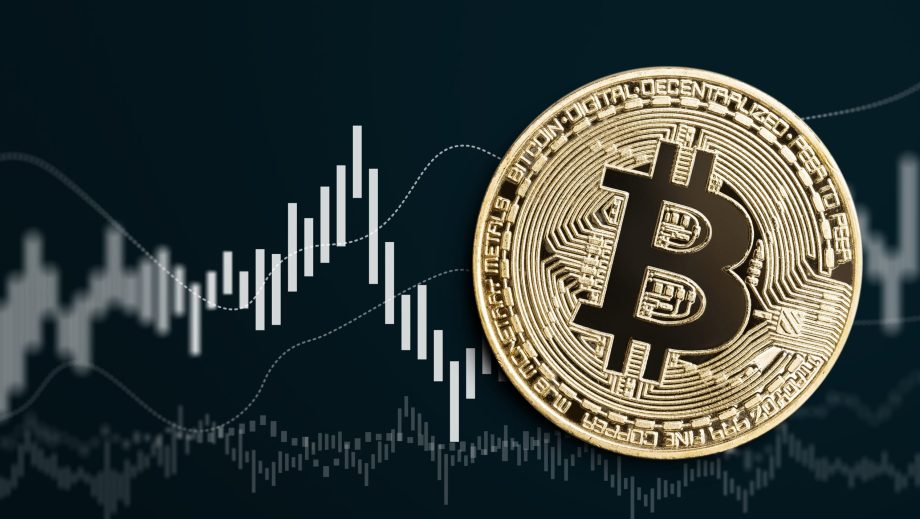 Bitcoin-Münze vor schwarzem Chartbild
