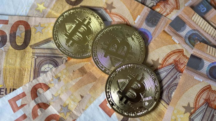 Das Bild zeigt Bitcoin-Münzen auf Euroscheinen