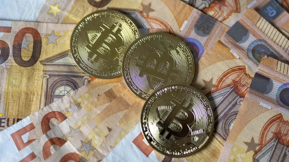 Das Bild zeigt Bitcoin-Münzen auf Euroscheinen