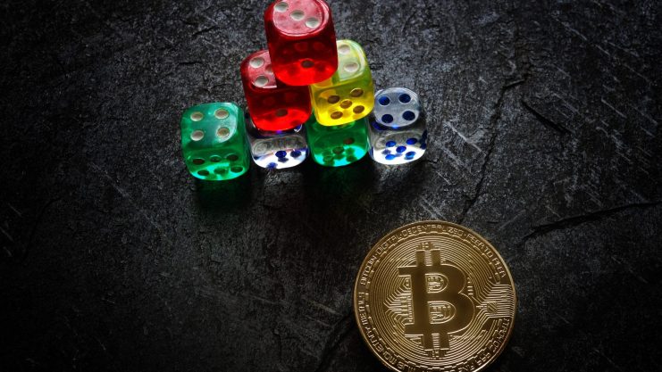 Das Bild zeigt eine Bitcoin-Münze und Würfel