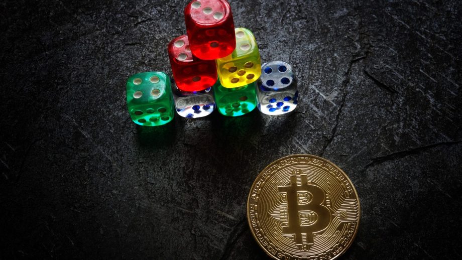 Das Bild zeigt eine Bitcoin-Münze und Würfel