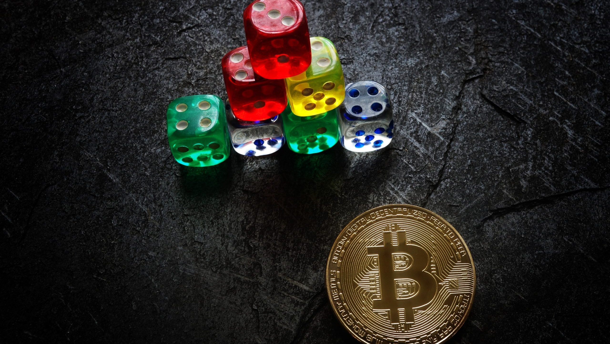 Das Bild zeigt eine Bitcoin-Münze und Würfel