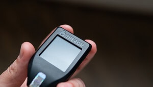 Eine Hand hält eine Trezor-Wallet