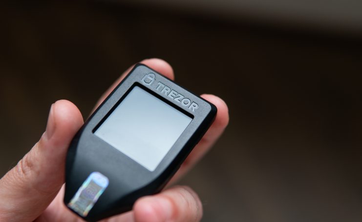 Eine Hand hält eine Trezor-Wallet