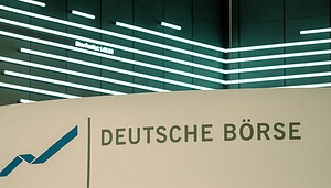 Ein Schild mit dem Logo und dem Namen der Deutschen Börse vor einer modernen, beleuchteten Wand mit horizontalen Lichtbändern unterstreicht den Fokus auf Innovation und Integration, einschließlich der Entwicklungen bei Stablecoins.
