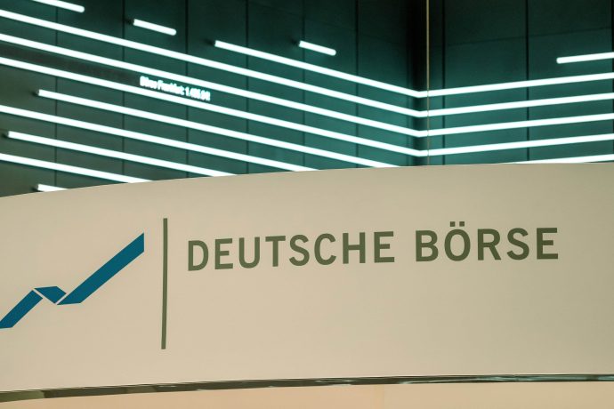 Ein Schild mit dem Logo und dem Namen der Deutschen Börse vor einer modernen, beleuchteten Wand mit horizontalen Lichtbändern unterstreicht den Fokus auf Innovation und Integration, einschließlich der Entwicklungen bei Stablecoins.