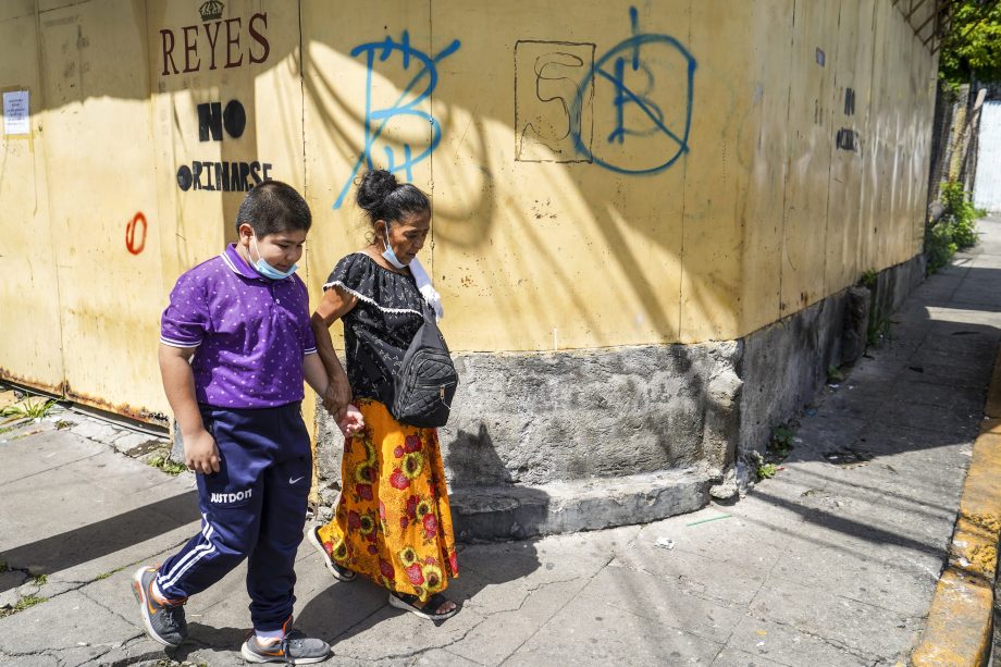 Eine Frau und ein Kind gehen am 4. September in San Salvador, El Salvador, an einem Schild vorbei, das vor der Nutzung von Bitcoin warnt. Am 7. September 2021 wurde El Salvador zum ersten Land, das eine Kryptowährung als gesetzliches Zahlungsmittel einführte, nachdem der salvadorianische Kongress beschlossen hatte, Bitcoin in dem mittelamerikanischen Land als Währung zuzulassen.