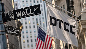 Wall-Street-Straßenschild in New York neben einer weißen Flagge mit DTCC-Logo und US-amerikanischen Flaggen im Hintergrund.
