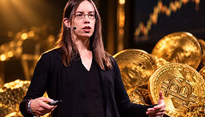 Lyn Alden bei einem Vortrag vor goldenen Bitcoin-Symbolen.