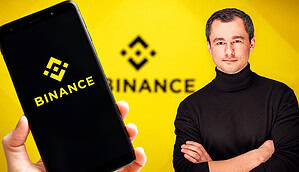 Binance Logo im Hintergrund und Binance Logo auf einem Smartphone links. Rechts steht ein Mann mit schwarzem Rollkragenpullover.
