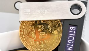 Das Bild zeigt eine Ledger Wallet und eine Bitcoin-Münze