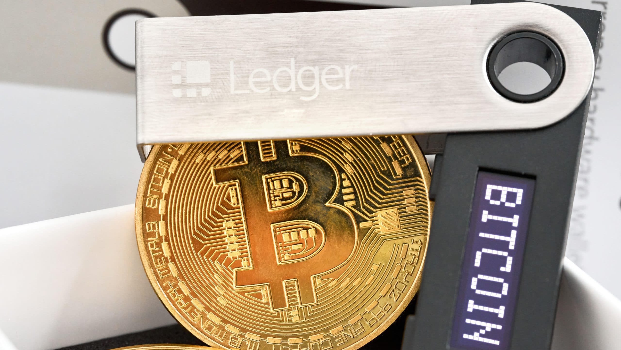 Das Bild zeigt eine Ledger Wallet und eine Bitcoin-Münze