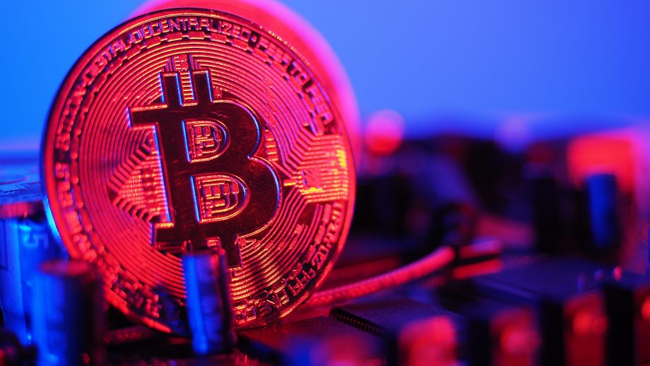 Eine rote Bitcoin-Münze vor blauem Hintergrund