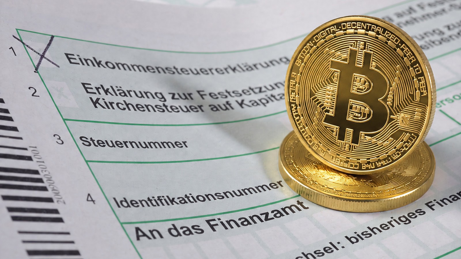 Man sieht ein deutsches Steuerformular und zwei Bitcoin-Münzen.