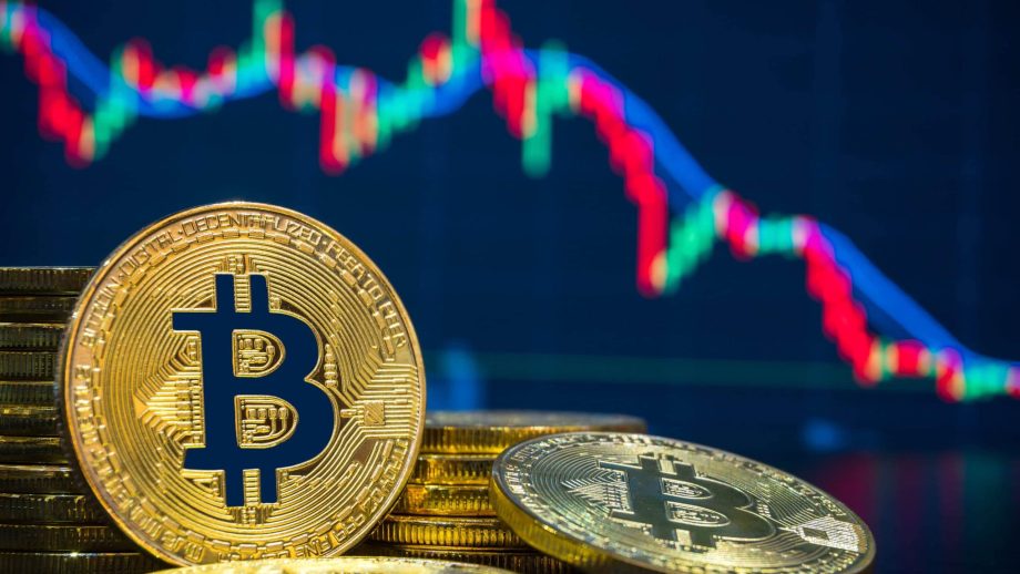 Bitcoin-Münzen vor einem fallenden Kurschart