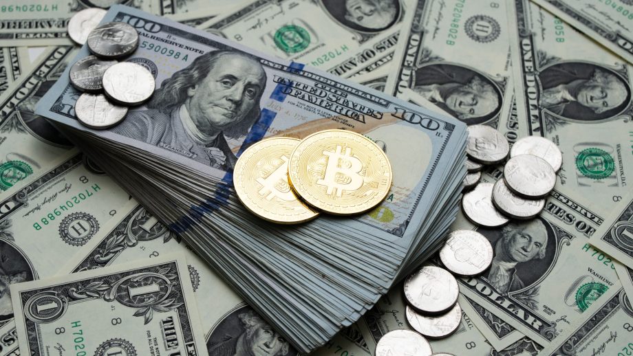 Das Bild zeigt eine goldene Bitcoin-Münze sowie US-Dollar