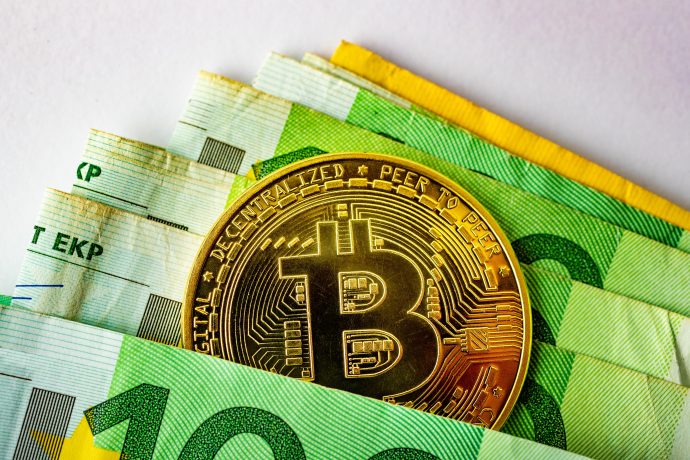 Bitcoin-Münze zwischen Euro-Banknoten