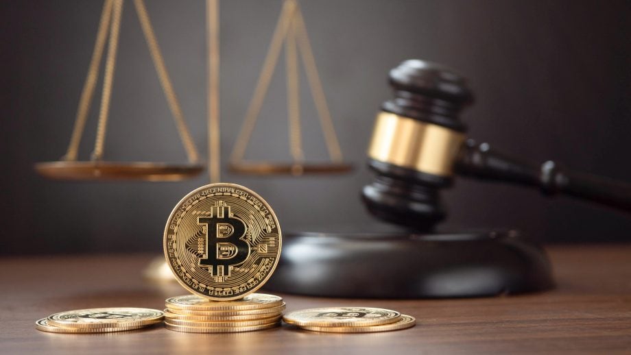 Hammer und Bitcoin Symbole auf braunem Tisch